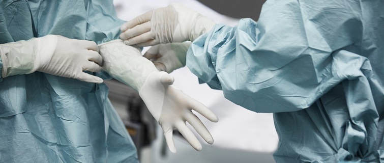 Doctor helping surgeon put on gloves