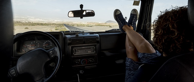 Woman sitting in car with feet on dashboard