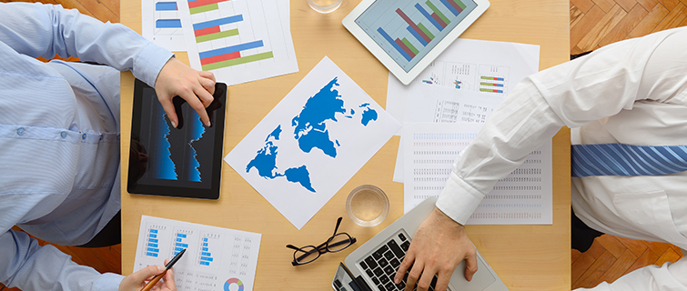 People work at a desk together, with charts and maps on the table